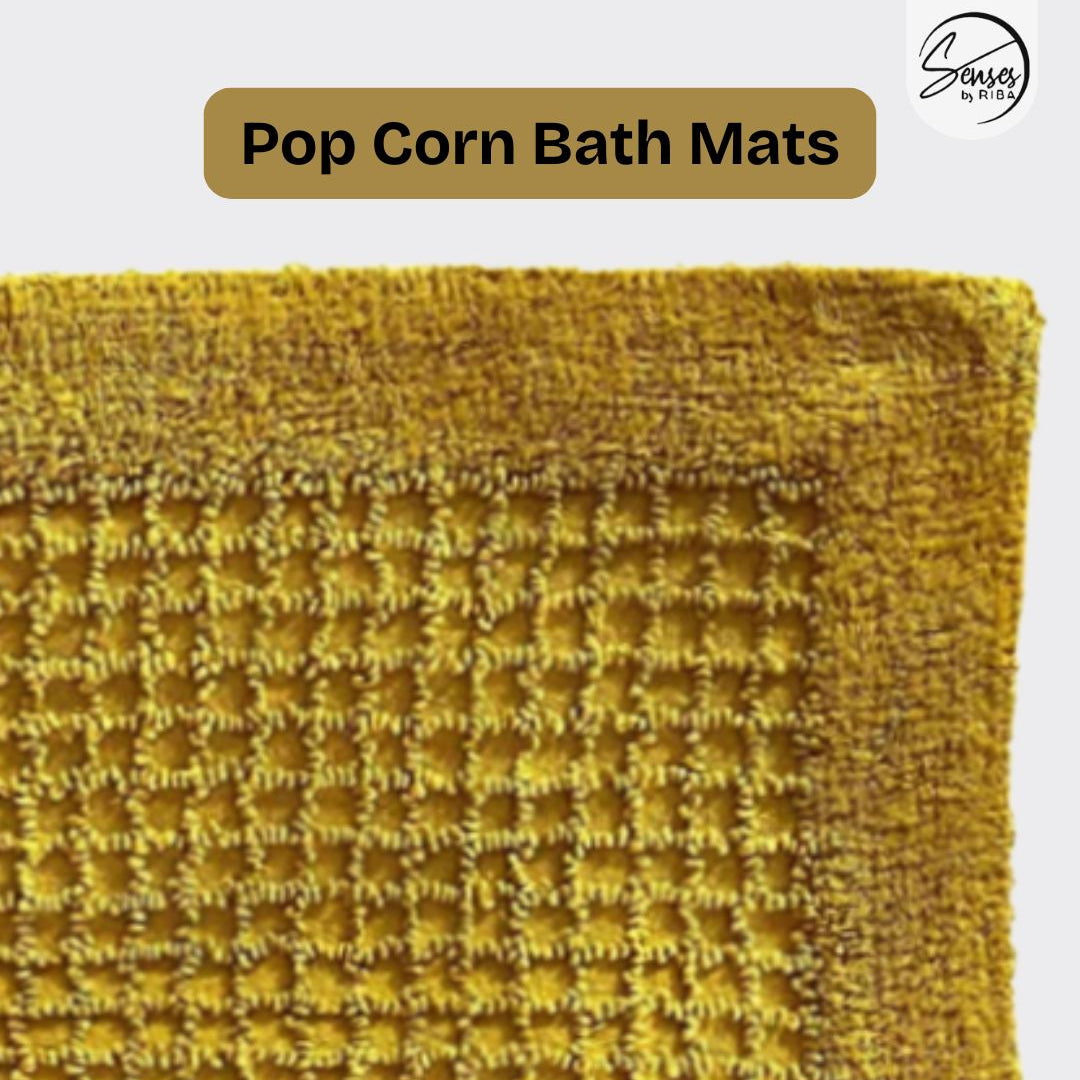 Yellow textured bath mat with 'Pop Corn Bath Mats' text and brand logo.